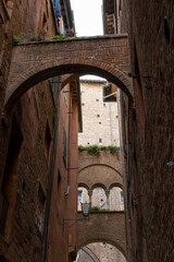 Siena old town street with arches and medieval buildings, Tuscany, Italy.