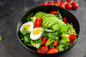 Salad avocado, boiled egg, tomato, green leaf lettuce, vegetable dish fresh gourmet food background on the table rustic food top view copy space vegetarian food