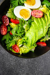 Salad avocado, boiled egg, tomato, green leaf lettuce, vegetable dish fresh gourmet food background on the table rustic food top view copy space vegetarian food