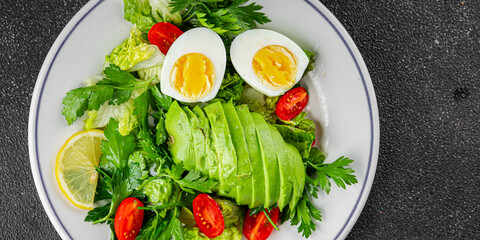Salad avocado, boiled egg, tomato, green leaf lettuce, vegetable dish fresh gourmet food background on the table rustic food top view copy space vegetarian food