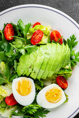 Salad avocado, boiled egg, tomato, green leaf lettuce, vegetable dish fresh gourmet food background on the table rustic food top view copy space vegetarian food
