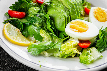 Salad avocado, boiled egg, tomato, green leaf lettuce, vegetable dish fresh gourmet food background on the table rustic food top view copy space vegetarian food