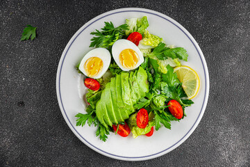 Salad avocado, boiled egg, tomato, green leaf lettuce, vegetable dish fresh gourmet food background on the table rustic food top view copy space vegetarian food