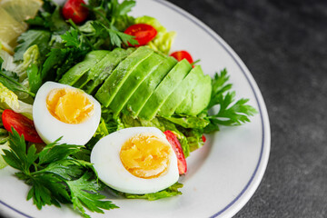 Salad avocado, boiled egg, tomato, green leaf lettuce, vegetable dish fresh gourmet food background on the table rustic food top view copy space vegetarian food