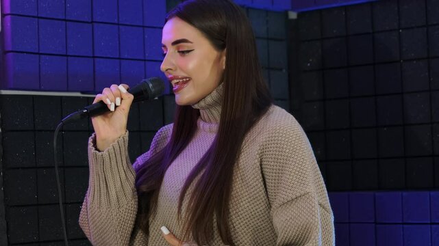 Young woman sings song in microphone in studio class. Student voice fills studio with rich timbre resonating with power and emotion slow motion