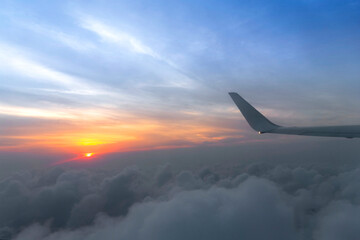 Wing of the air plane on the sea of cloud sunset sky background from window airplane