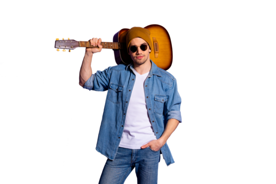 Photo of confident attractive handsome man wearing brown cap spectacles standing with guitar on his shoulder and hand in pocket isolated over purple vibrant color background