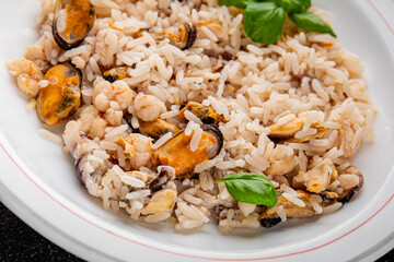 Rice seafood risotto mussels, shrimp, prawn, rapan, squid vegetable dish fresh gourmet food background on the table rustic food top view copy space