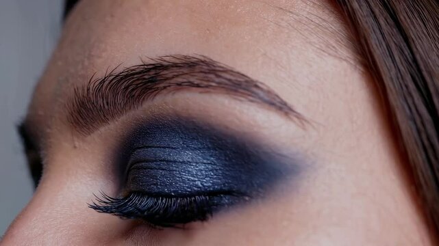 Closeup of glamorous smokey eye makeup application with dramatic blue eyeshadow and eyeliner focus