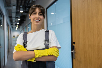 Smiling dark-haired caucasian young girl from cleaning team in yellow gloves looking confident
