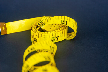 Close up view of yellow measure tape on dark background with customizable space for text. Dieting and copy space concept