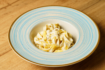 Classic spaghetti cacio e pepe with grated cheese on a blue-striped plate