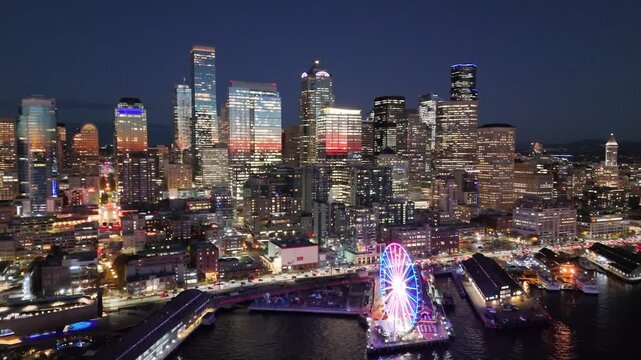 A breathtaking aerial night view of downtown Seattle, Washington, showcasing the illuminated skyline and iconic skyscrapers. Glowing Seattle Great Wheel. Seattle at night. Top cinematic aerial view