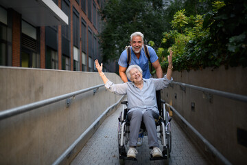 Male caregiver pushing senior woman in wheelchair.