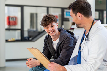Teenage boy smiling talking with doctor, receiving positive health news.