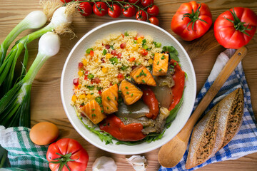 Dish with baked salmon, peppers and couscous salad. Top view table.