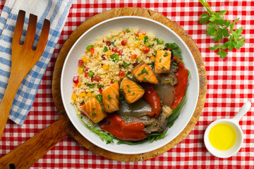 Dish with baked salmon, peppers and couscous salad. Top view table.