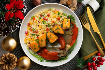 Dish with baked salmon, peppers and couscous salad. Top view table with christmas decorations.