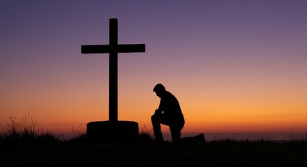 Silhouette of a man praying at the base of a large cross against a colorful sky.