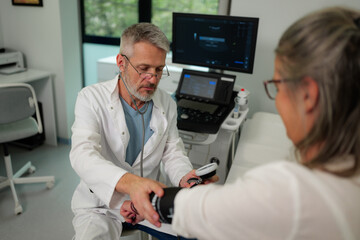 Male doctor measuring blood pressure of female patient with a sphygmomanometer during a thorough...