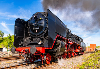Historic german express steam locomotive of the legendary class 01 in action. Lovingly restored vintage railcar from a frog's-eye view. German railroad technology maintained by hobby enthusiasts.