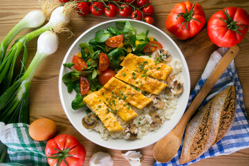 Dish with an omelet filled with cheese, rice and salad. Top view table.