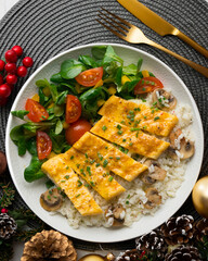Dish with an omelet filled with cheese, rice and salad. Top view table with christmas decorations.