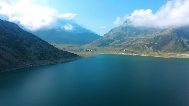 Drone View Stunning Lago di Montespluga Remote Alpine Lake and Village Dramatic Rocky Mountains Under Blue Sky Nature Travel Destination