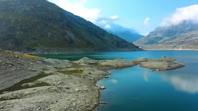 Drone View Stunning Lago di Montespluga Remote Alpine Lake and Village Dramatic Rocky Mountains Under Blue Sky Nature Travel Destination
