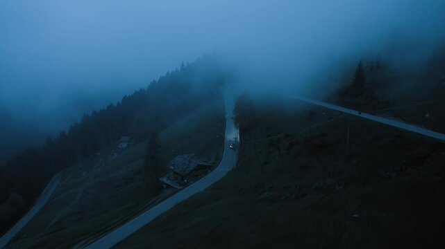 Aerial Drone View Cars Driving Winding Road in Fog and Darkness Remote Mountain Landscape Headlights Piercing Mist Solitary Night Journey