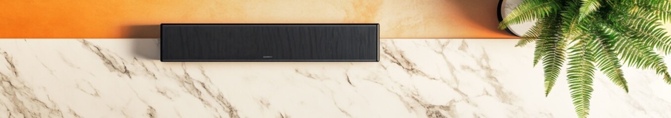 A flat lay of a black soundbar on a white marble countertop, with an orange and beige border