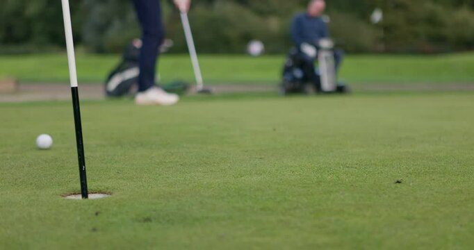 Feet, golf club and ball for shot on grass, pitch or course with training for competition, game or challenge. Para golfing, people or professional for sports by active with hobby, recreation or ready