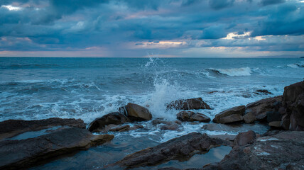 Obraz premium Churning waves strike rocks in a turbulent sea