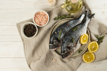 Fresh dorado fish with lemon, rosemary and spices on a plate, close up