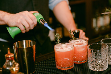 Bartender preparing cocktails with a torch at a bar in the evening