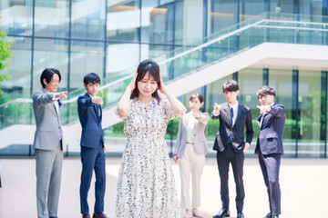 同僚に責められて頭を抱える女性のビジネスパーソン