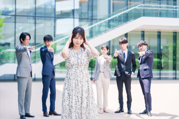 同僚に責められて頭を抱える女性のビジネスパーソン