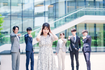 同僚に責められて頭を抱える女性のビジネスパーソン