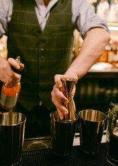 Bartender prepares a cocktail using jigger at a bustling bar during the evening rush peak