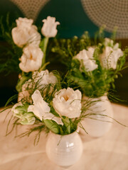 Elegant white flowers arranged in vases on a table in a cozy indoor setting during evening hours