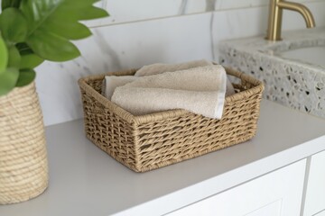 Rustic wicker basket with towels on modern bathroom vanity countertop