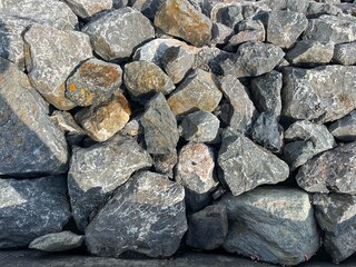 Sea shore surface close-up. Distressed, сracked, collapsed, crumbled, broken. Big Rock stones, gravel. Background. Textures Dark gray stone. 