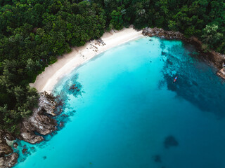 Aerial view of Banana Beach, Phuket, Thailand, with turquoise water, white sand, and lush tropical forest.