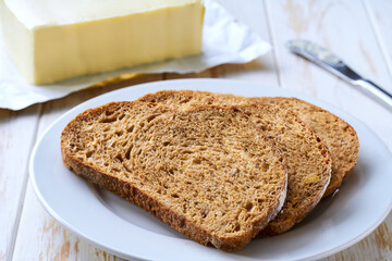 slices rye bread and piece of butter, on a light table selective focus.