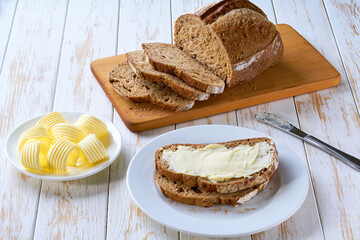 multigrain sourdough bread slices  and butter on wooden table, top view.