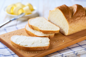 Delicious white wheat bread and fresh butter on cutting board.