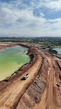 V&iacute;deo vertical com vis&atilde;o a&eacute;rea de um caminh&atilde;o atravessando uma mineradora. A cena captura o transporte de min&eacute;rio e o processo industrial dentro da minera&ccedil;&atilde;o, mostrando a infraestrutura pesada