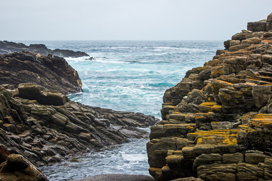 Looking throught the tiltel rocks of the Tsitsikama coast, south Africa, at the grey and cyan colored oceon on a cold overcast Morning