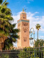 Koutoubia Mosque minaret in Marrakesh, Morocco, surrounded by palm trees under bright blue sky, showcasing historic Islamic architecture, cultural heritage, religious significance and vibrant scenery.