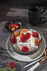 Creamed cottage cheese with raspberries. An easy healthy breakfast. A bowl filled with grainy, creamy cottage cheese is garnished with bright yellow and red raspberries